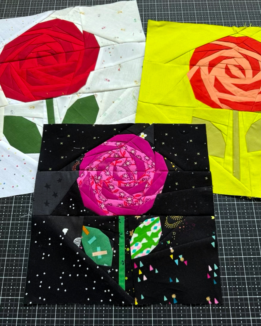 Three quilt blocks with rose designs on a grid background