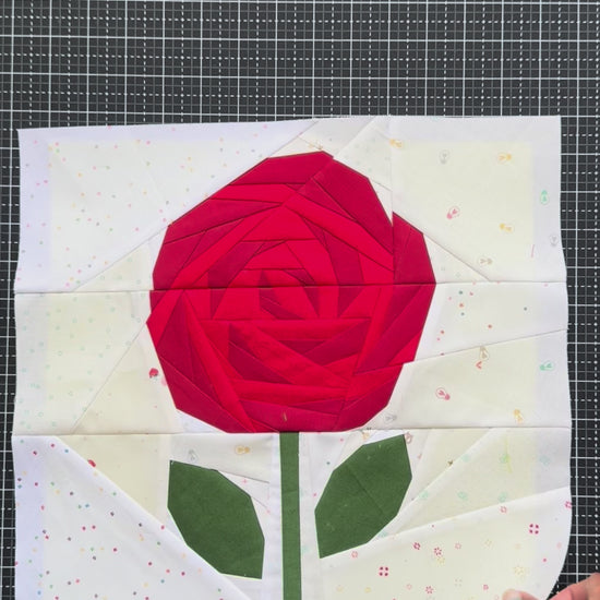 Video of three quilt blocks with rose designs on a grid background